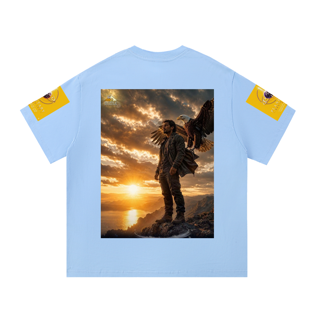 A light blue short-sleeve t-shirt with a large rectangular graphic print on the back showing a man with a large eagle at sunset, with yellow graphic patches on both sleeves.