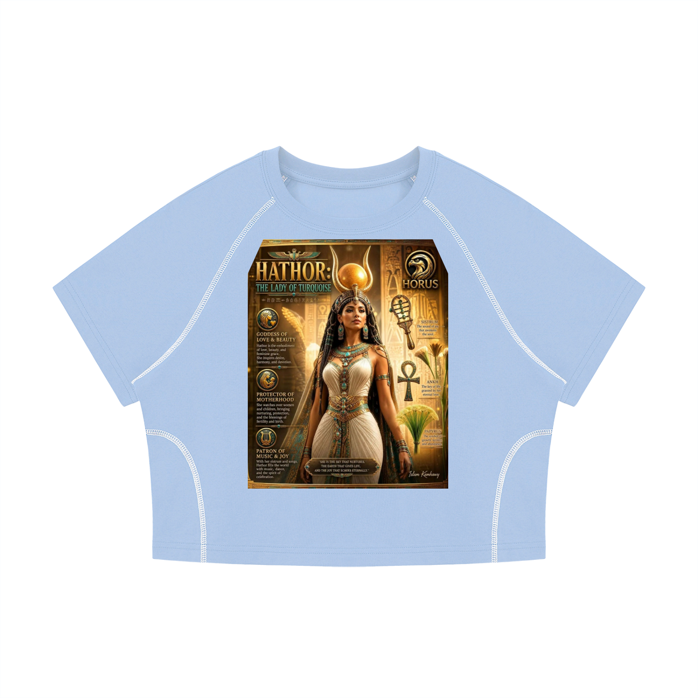 A light blue cropped t-shirt with white contrast stitching along the raglan sleeves and sides, featuring a large rectangular graphic print on the front depicting an Egyptian goddess with the text 'HATHOR THE DEITY' and the 'HORUS' brand logo.
