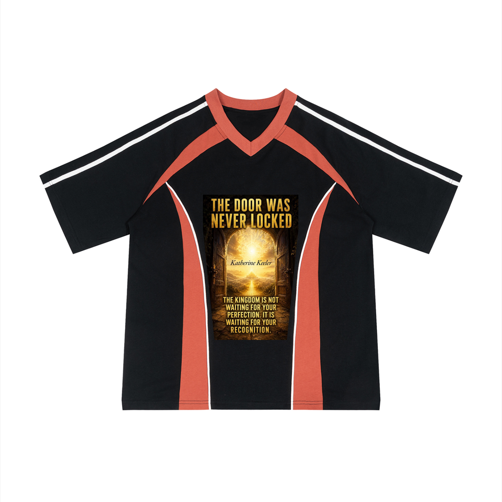 A black short-sleeve V-neck athletic-style shirt with coral orange shoulder and side panels, white stripes on the sleeves, and a large golden-yellow graphic print on the chest reading 'THE DOOR WAS NEVER LOCKED' with additional text below.