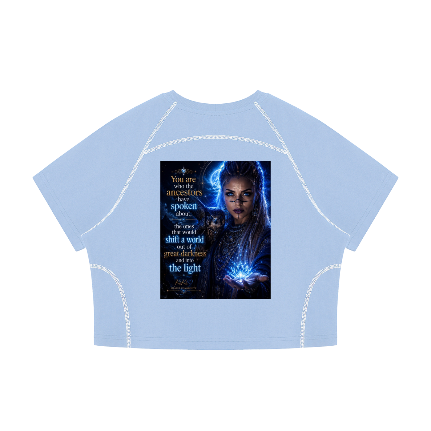 A light blue cropped short-sleeve t-shirt with white contrast stitching along the seams, featuring a large graphic print on the front depicting a woman with glowing blue energy and text.