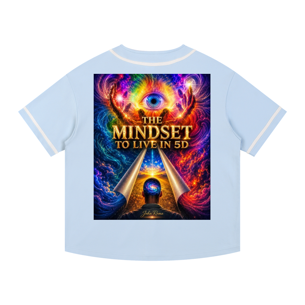 A light blue short-sleeve t-shirt with white contrast stitching on the collar and cuffs, featuring a large, vibrant graphic print on the front. The graphic displays a cosmic eye, glowing hands, and the text 'THE MINDSET TO LIVE IN 5D' in gold lettering.