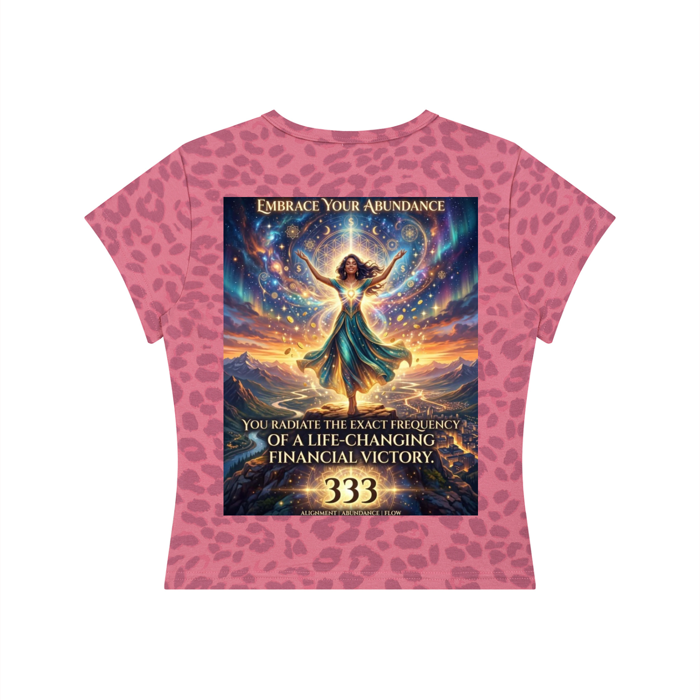 A pink short-sleeve t-shirt with a leopard print pattern and a large central graphic print. The graphic features a fantasy illustration of a woman surrounded by a golden aura and stars, with text that reads 'EMBRACE YOUR ABUNDANCE' and 'YOU RADIATE THE EXACT FREQUENCY OF A LIFE-CHANGING FINANCIAL VICTORY.